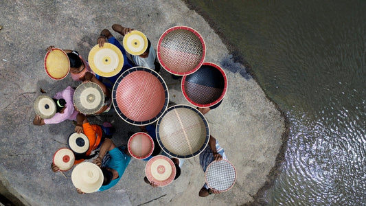 Artigiani e artigiane latinoamericani espongono le loro creazioni intrecciate a mano lungo un fiume, testimonianza del valore umano, culturale e artistico dell'artigianato tradizionale